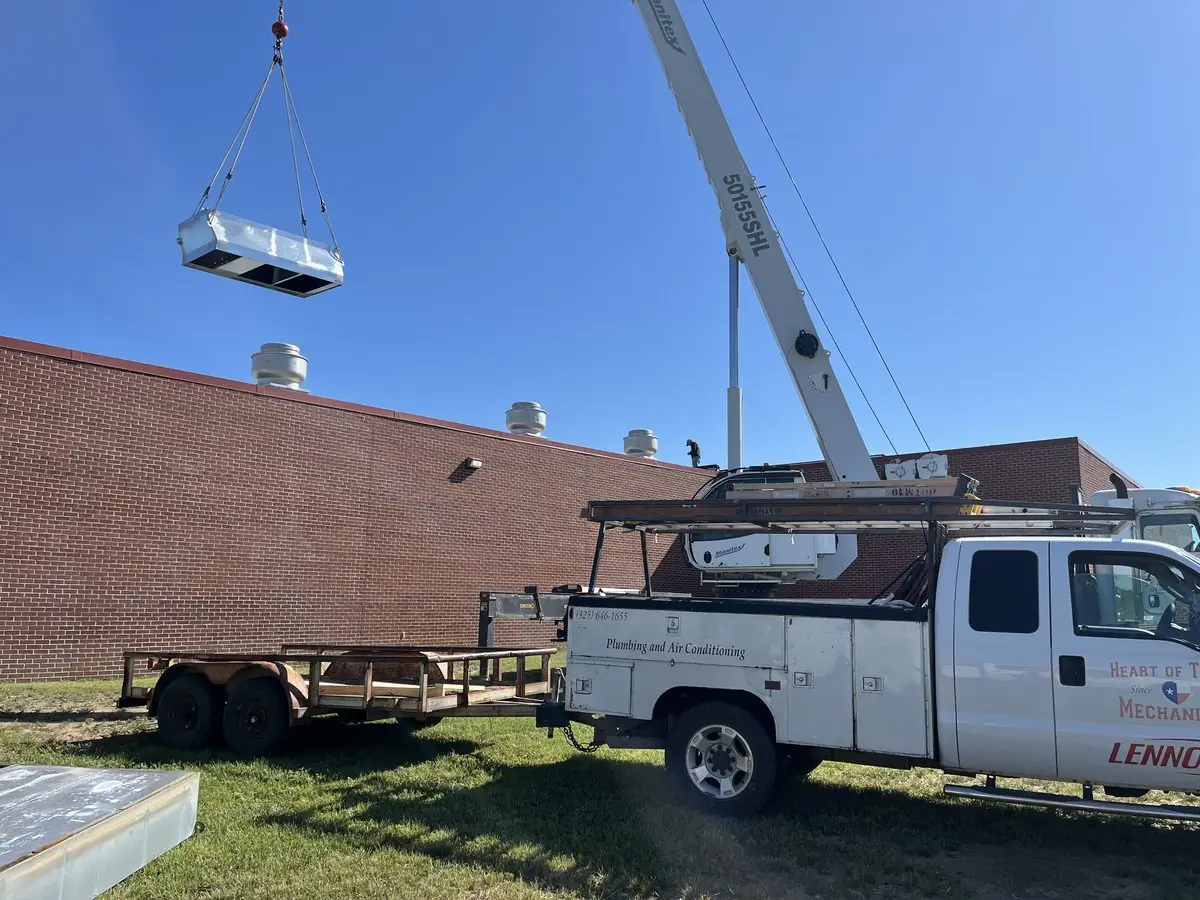 Crane lifting a new rooftop HVAC unit onto a commercial building