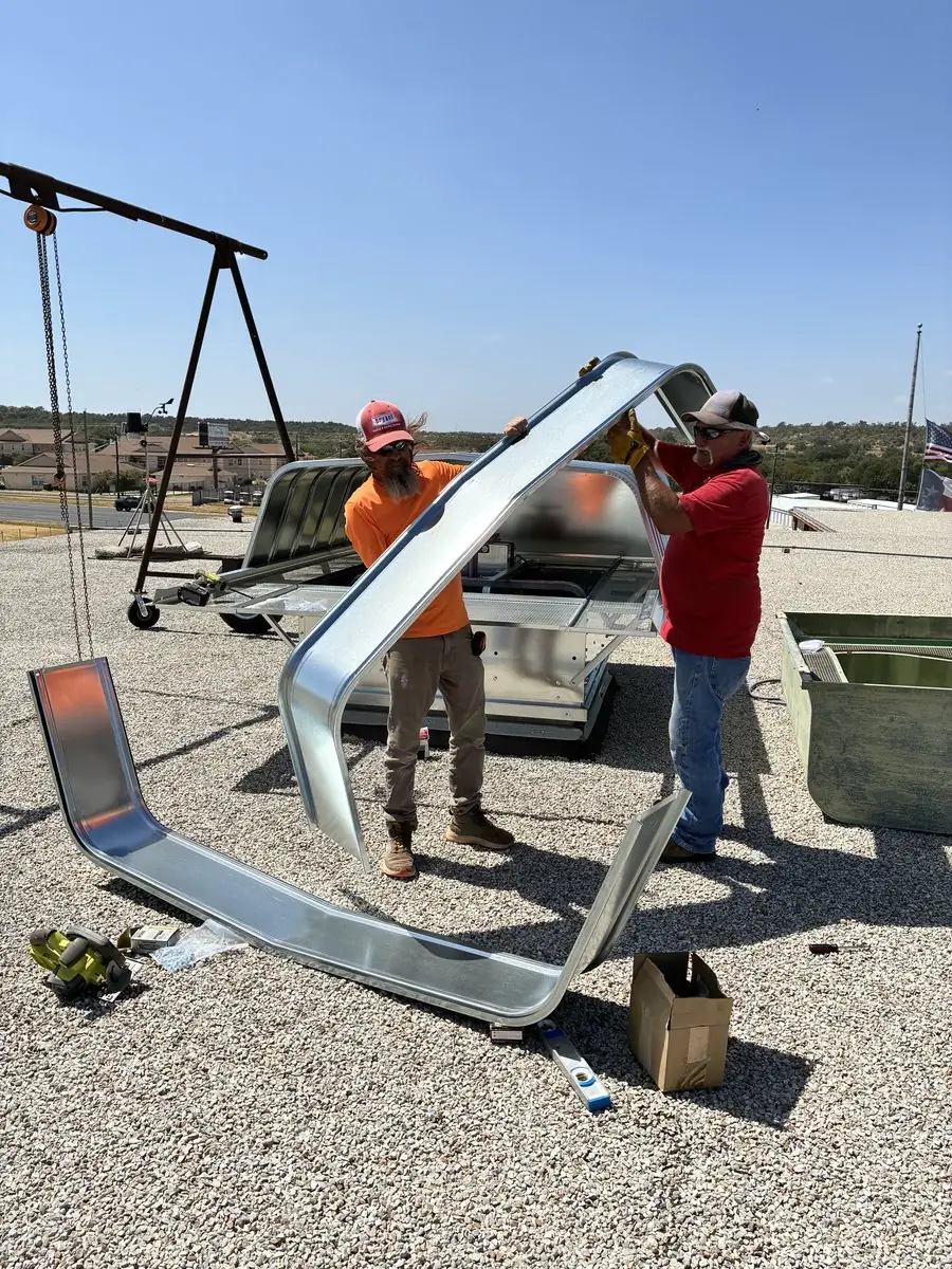 Technicians fitting a duct transition on a roof