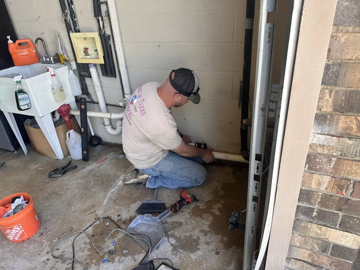 Heart of Texas Mechanical technician repairing plumbing in a home garage