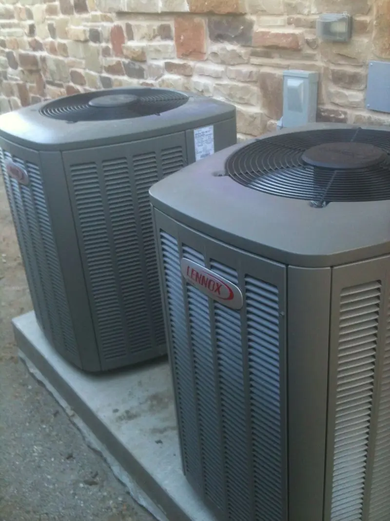 Two Lennox outdoor AC units beside a home